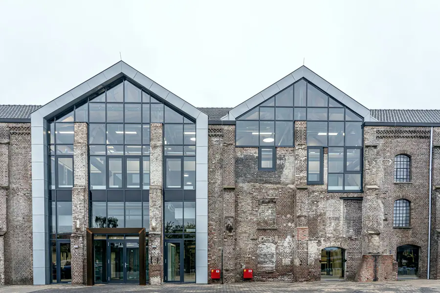 A restored brick warehouse with two tall glass gables over the main entrance and arched windows along the old brick wall.