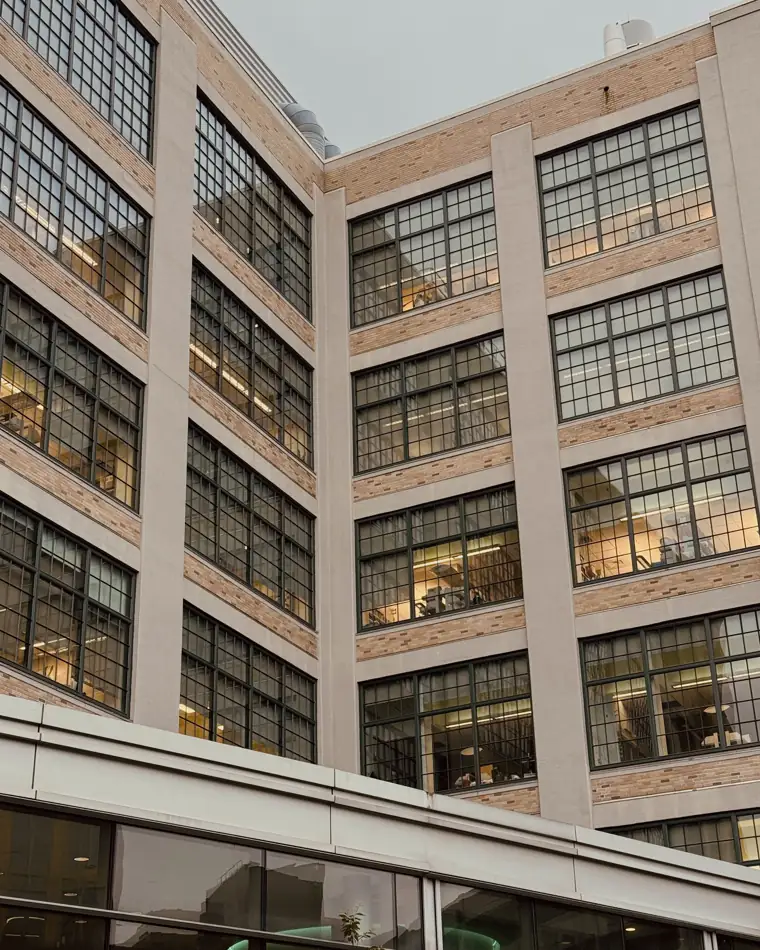 A pale concrete-frame loft building with large grid windows, seen from the courtyard below.